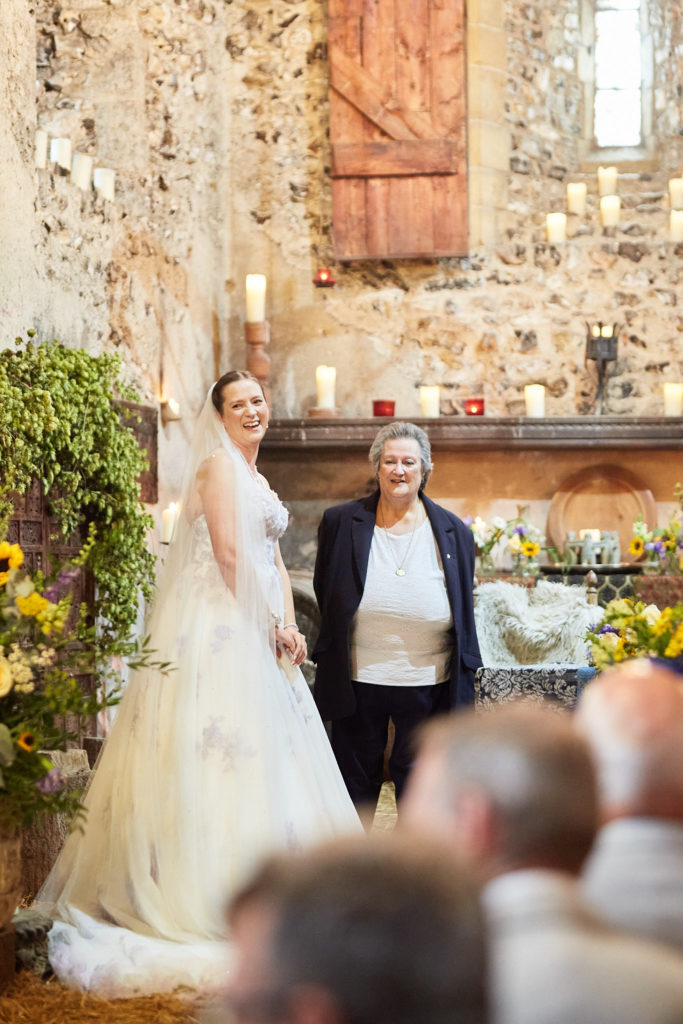 Bride smiling beside the celebrant in the candlelit church