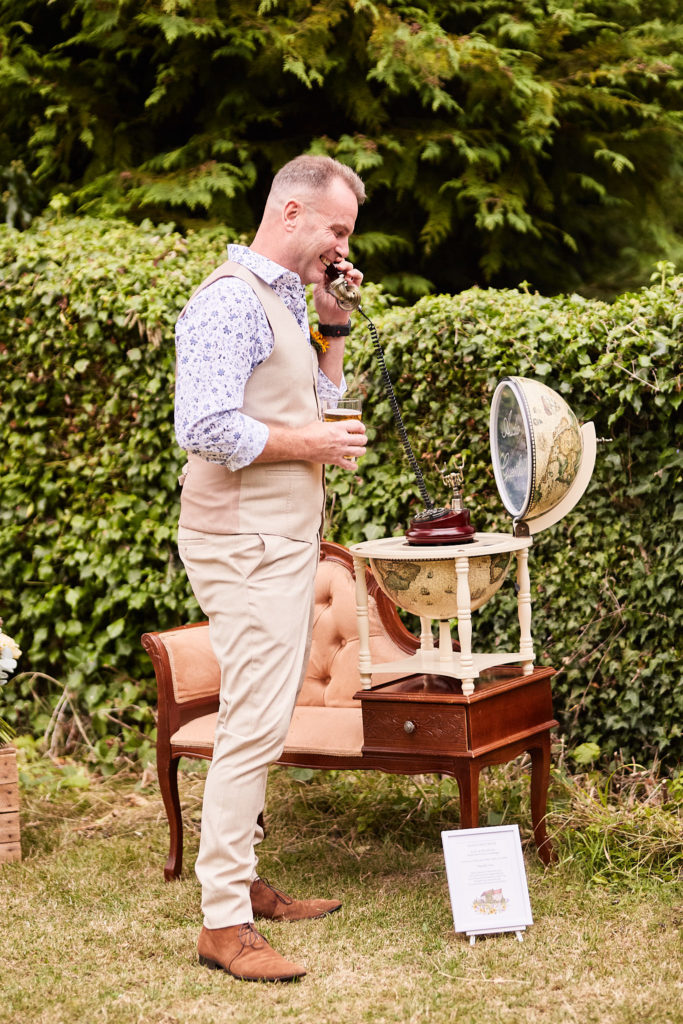 Groom leaving a message on a vintage telephone guest book on the lawn