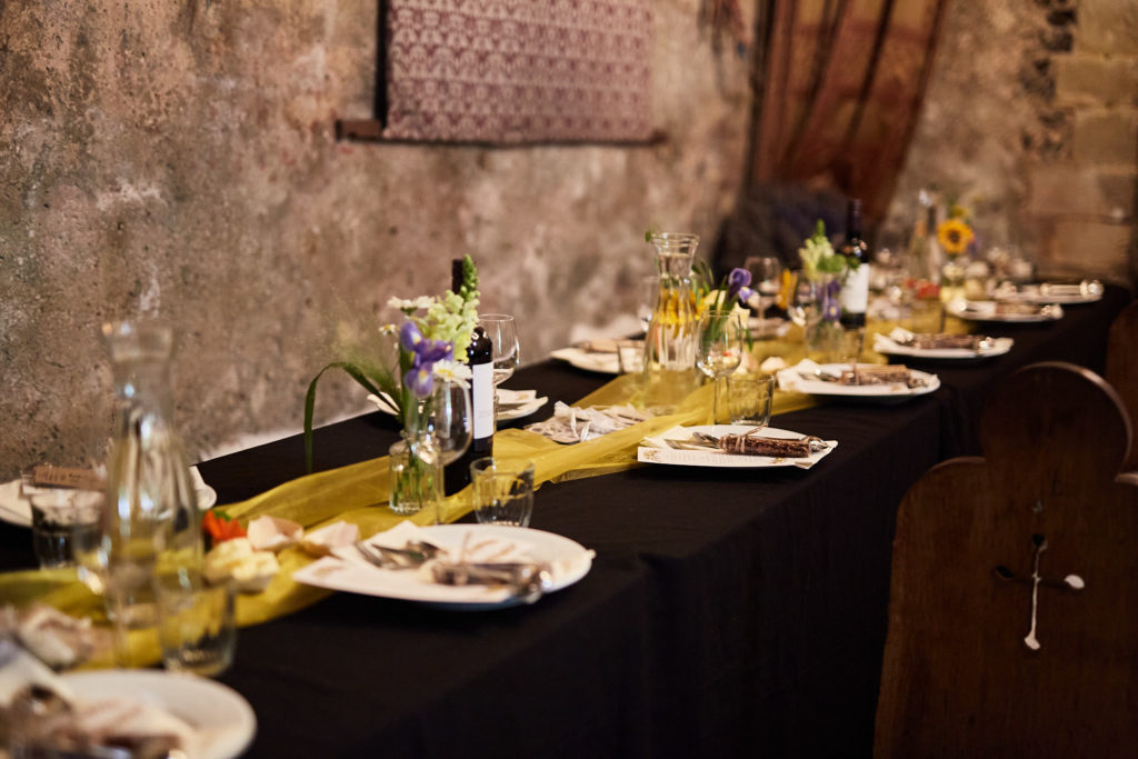Long banquet table set for the wedding breakfast inside the flint-walled church