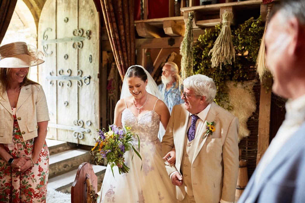 Bride arriving at the church arm in arm with an elderly man in a cream suit