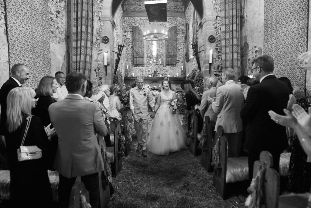 Black and white photo of guests standing as the bride enters the church