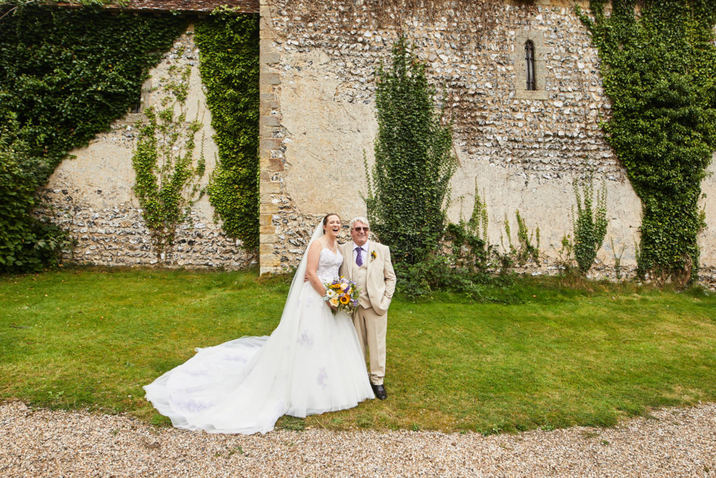 Bride and groom in front of the ivy-covered flint church at the Lost Village of Dode