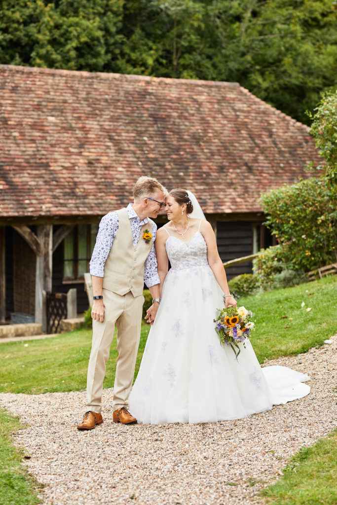 Bride and groom forehead to forehead beside the timber barn at the Lost Village of Dode