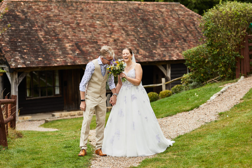 Bride and groom walking along the path by the barn at the Lost Village of Dode