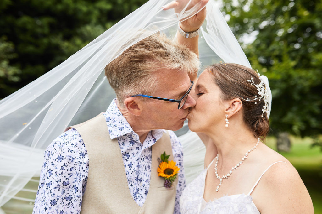 Bride and groom kissing beneath her veil