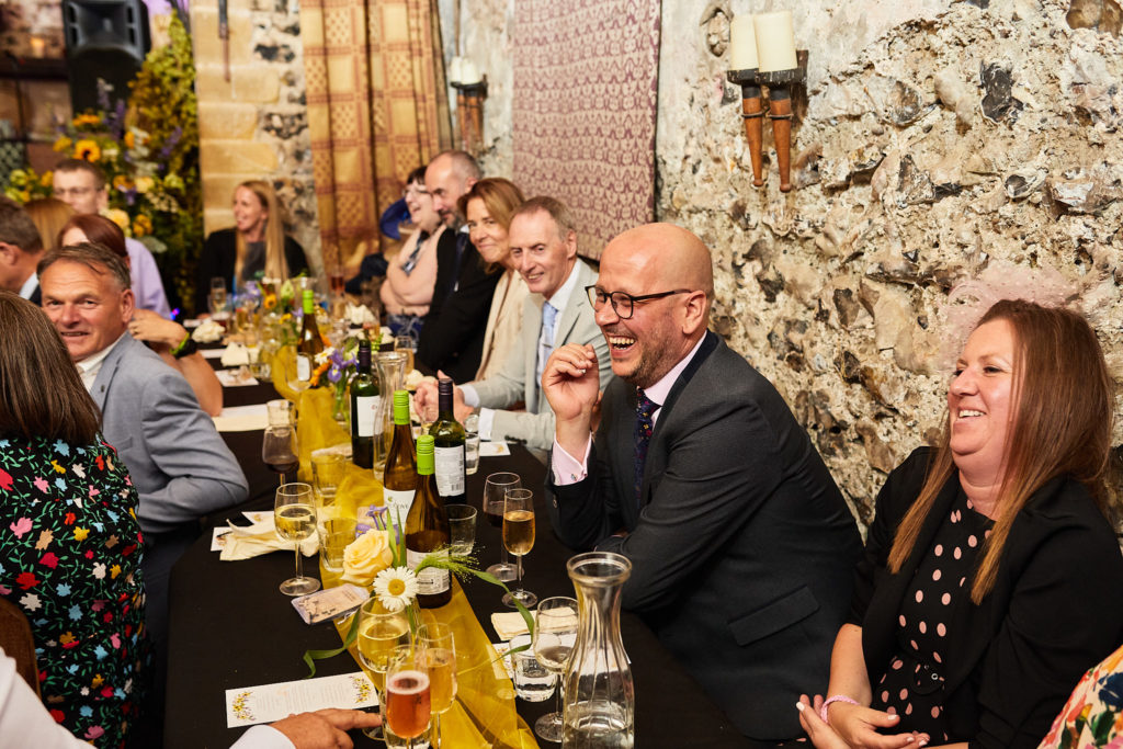 Wedding guests laughing along a long banquet table