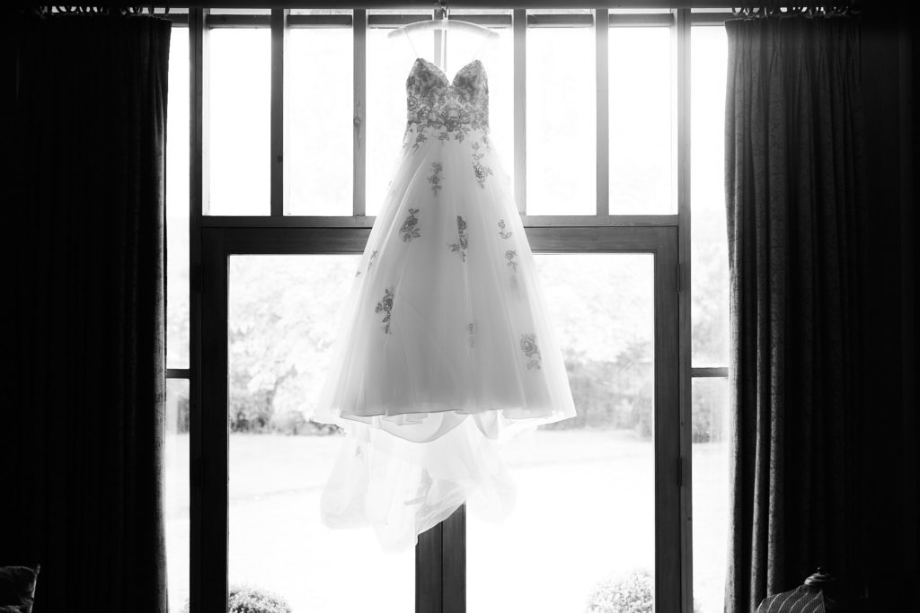 Black and white photo of the wedding dress hanging in a window