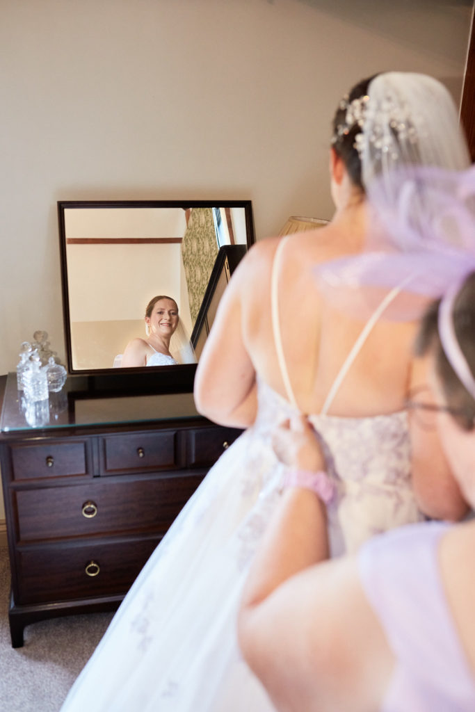 Bride's wedding dress being laced up at the back