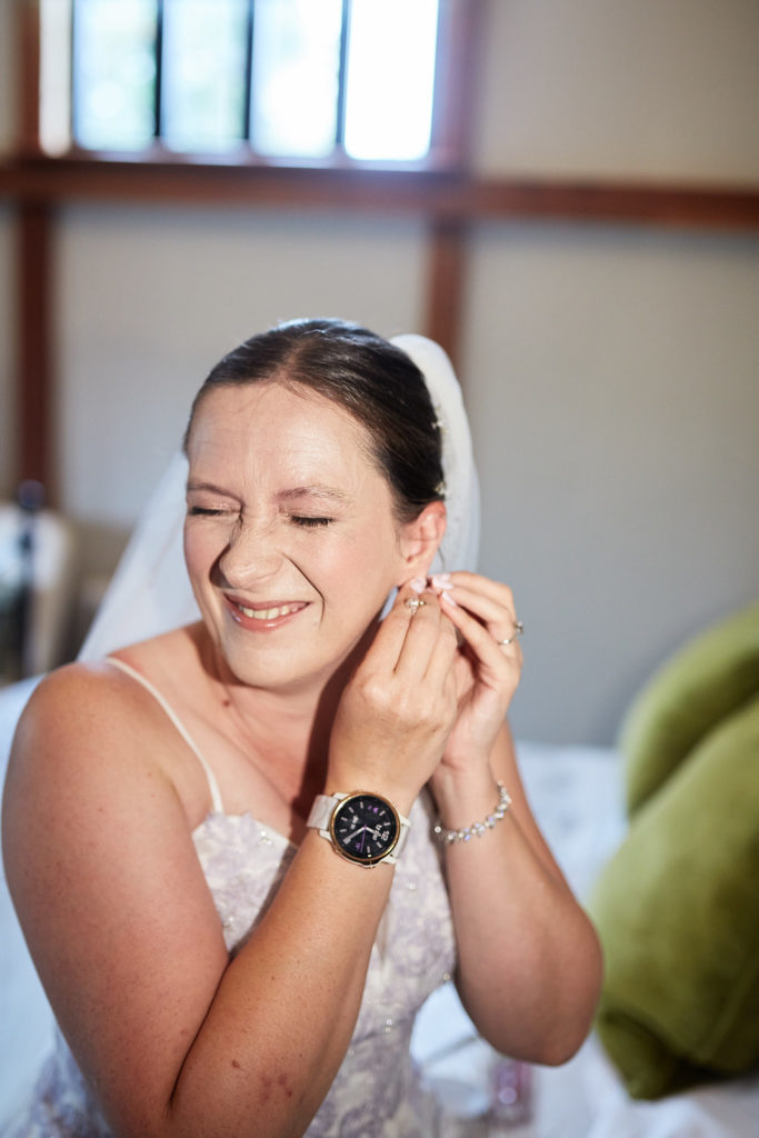 Bride smiling as she puts in her earring