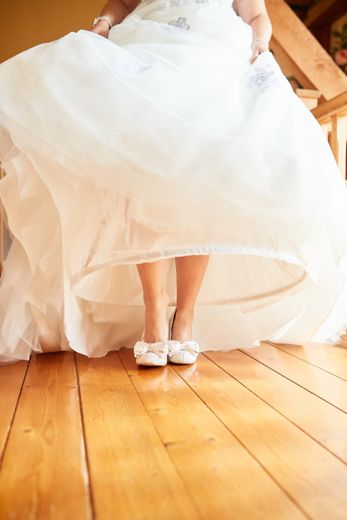 Bride lifting the hem of her dress to show her shoes