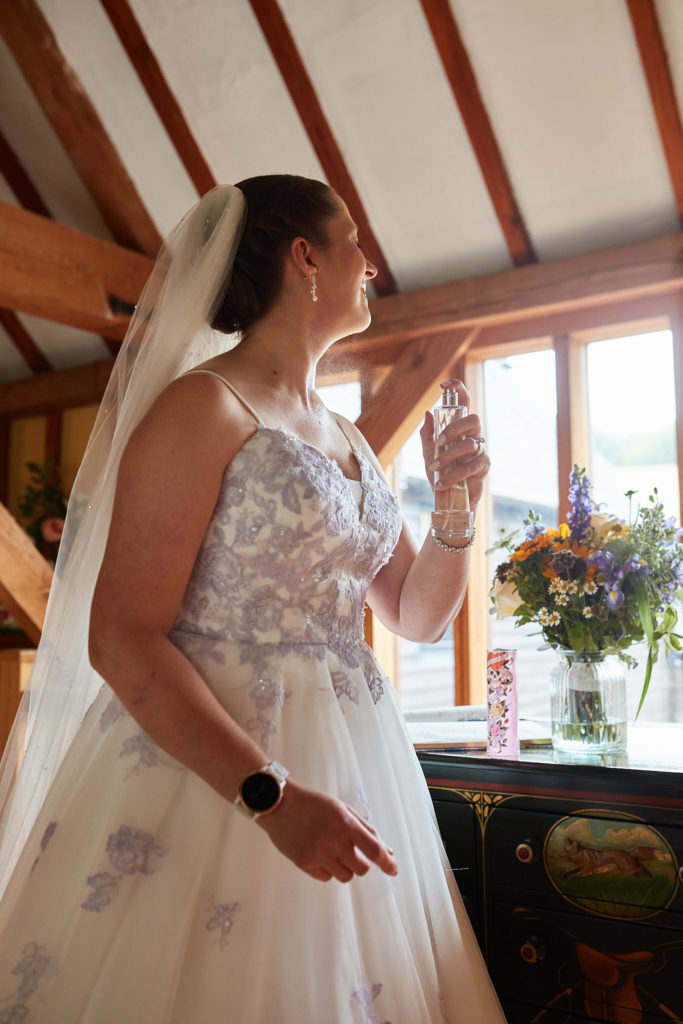 Bride in her wedding dress looking out of a window in an oak-beamed room