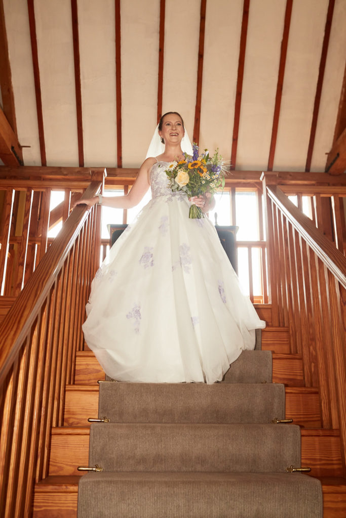 Bride at the top of a wooden staircase with her bouquet