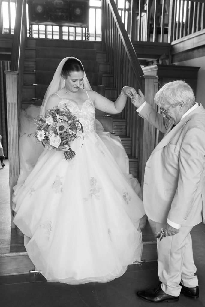Black and white photo of an elderly man helping the bride down the stairs