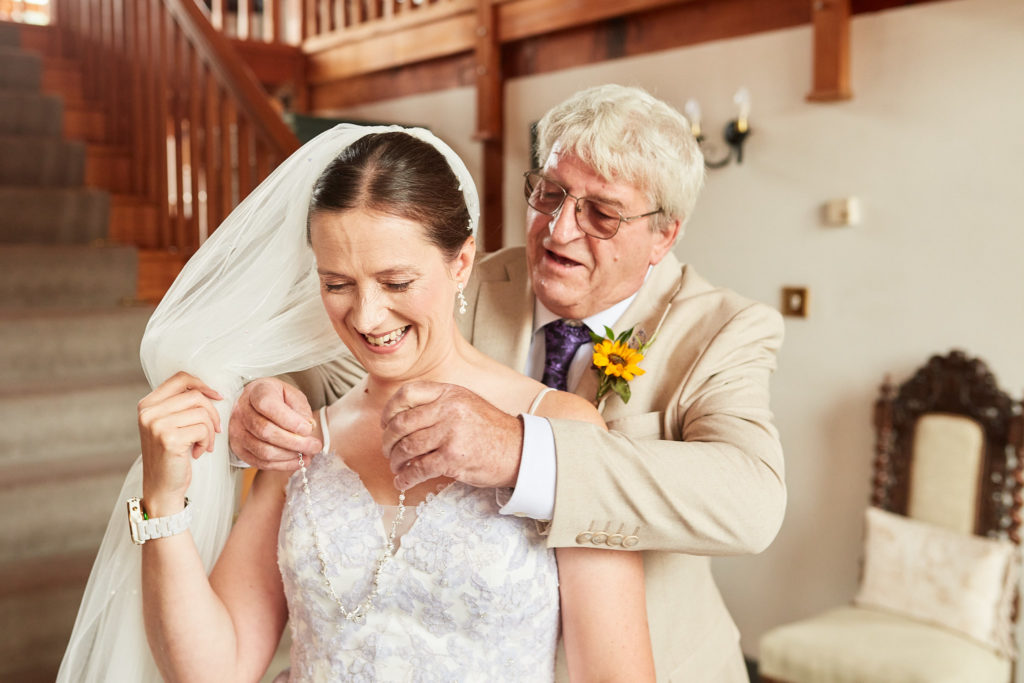 Elderly man in a cream suit hugging the laughing bride