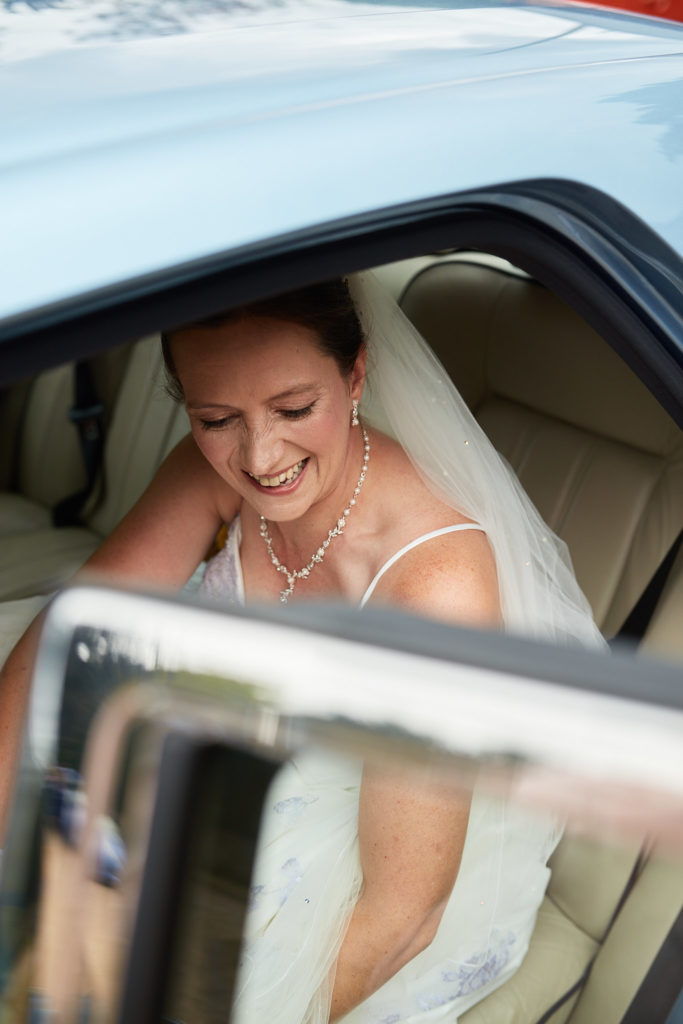 Bride smiling as she gets out of the wedding car