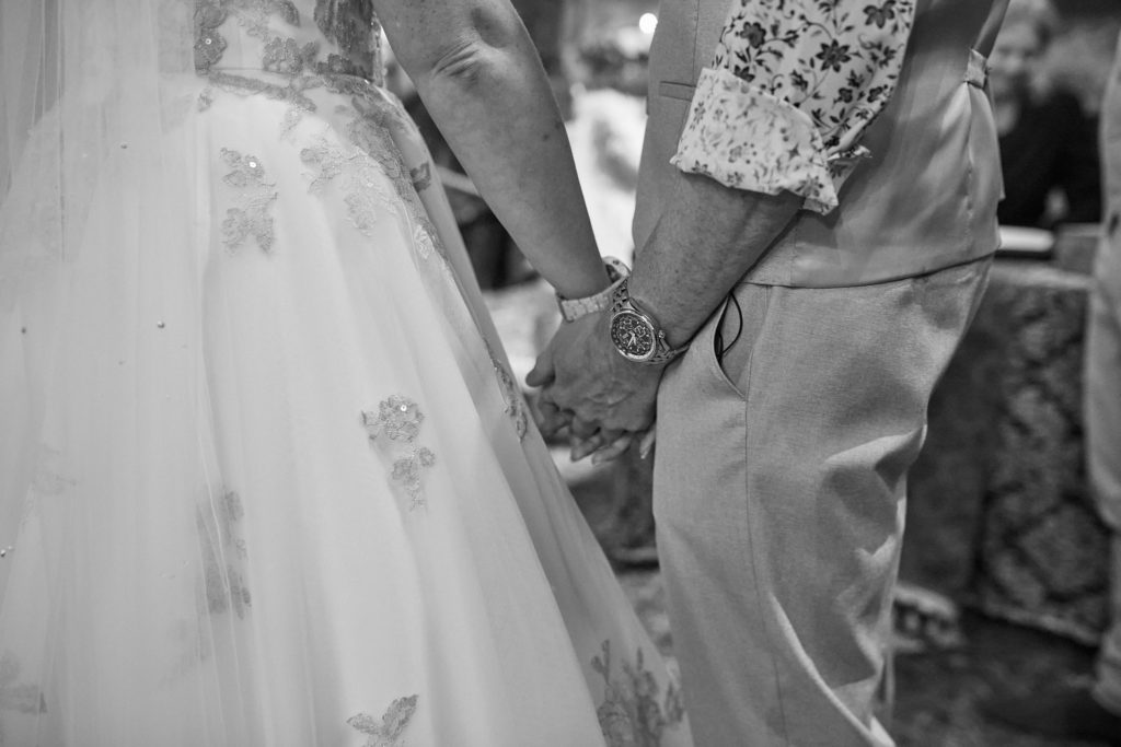 Black and white close-up of the bride and groom holding hands