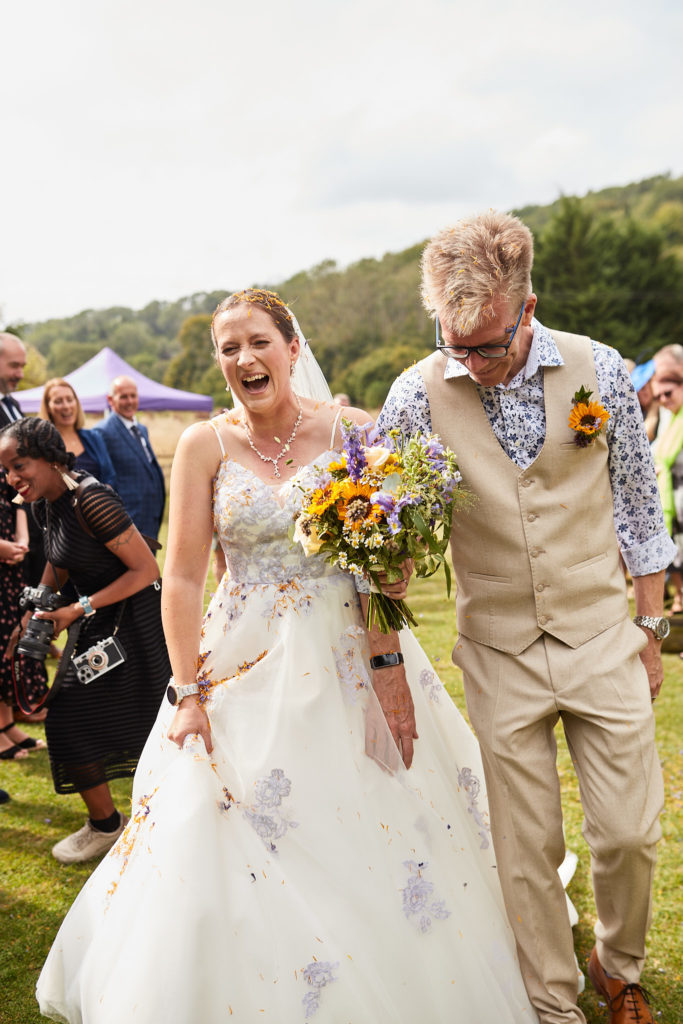 Bride and groom laughing as guests throw confetti