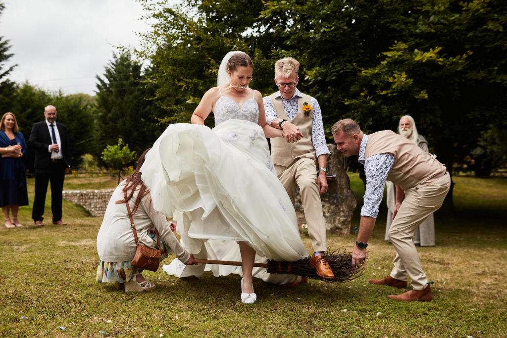 Bride and groom jumping the broom on the lawn