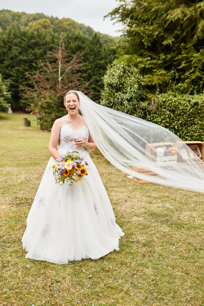 Bride laughing as her veil blows out in the wind