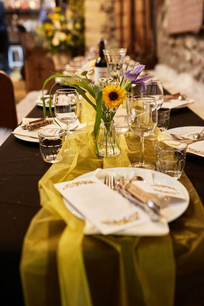 Table setting with a sunflower in a glass vase and a yellow runner