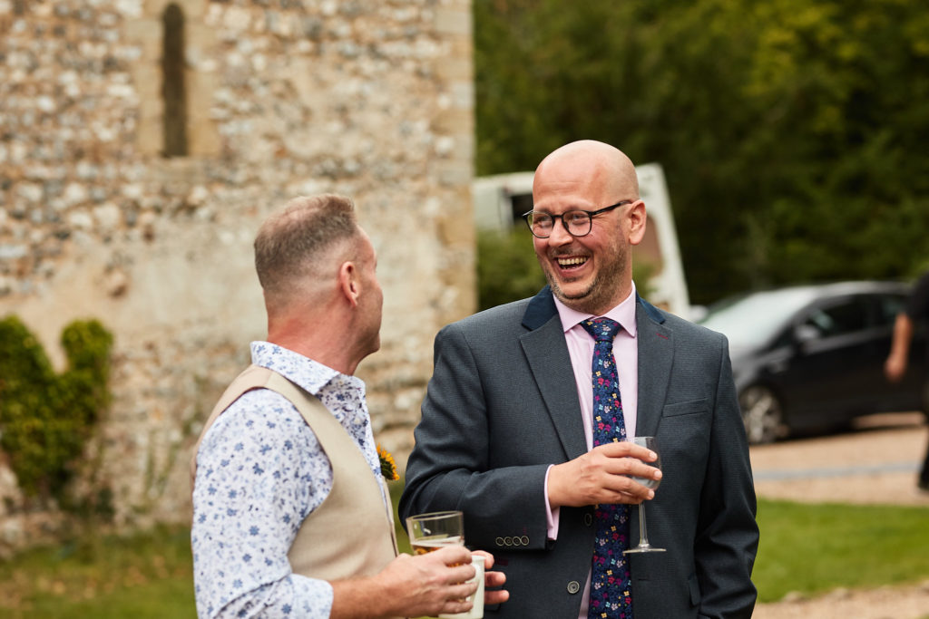 Groom laughing with a guest outside the church