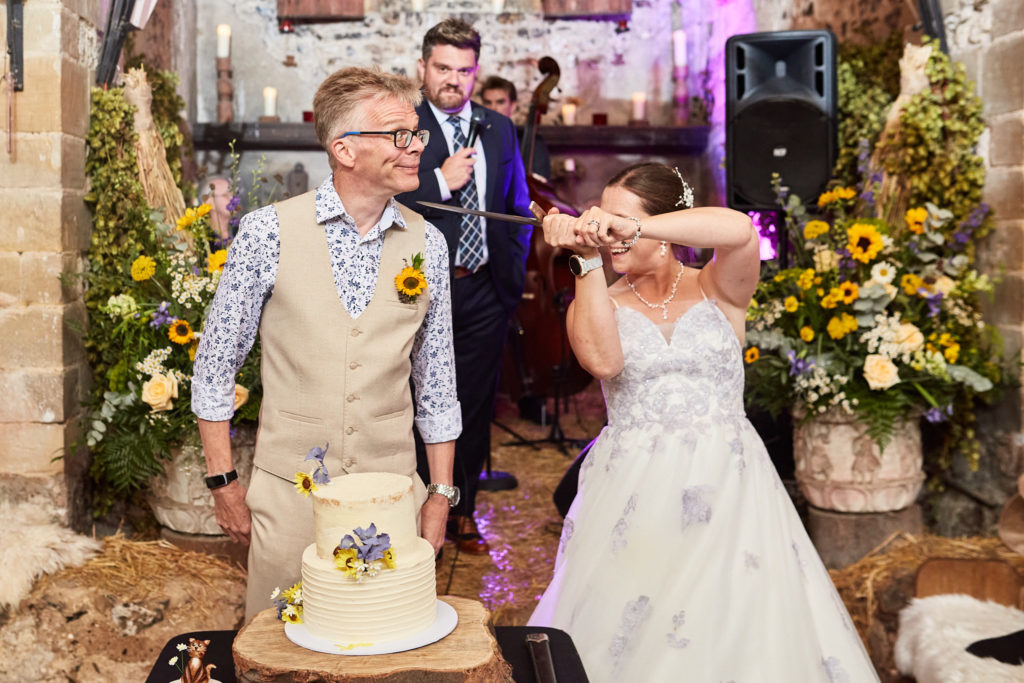 Bride and groom drinking a toast beside their wedding cake