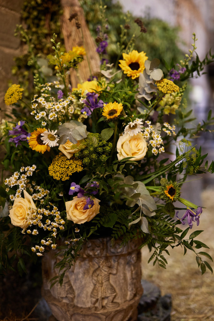 Large arrangement of sunflowers and wildflowers in a stone urn