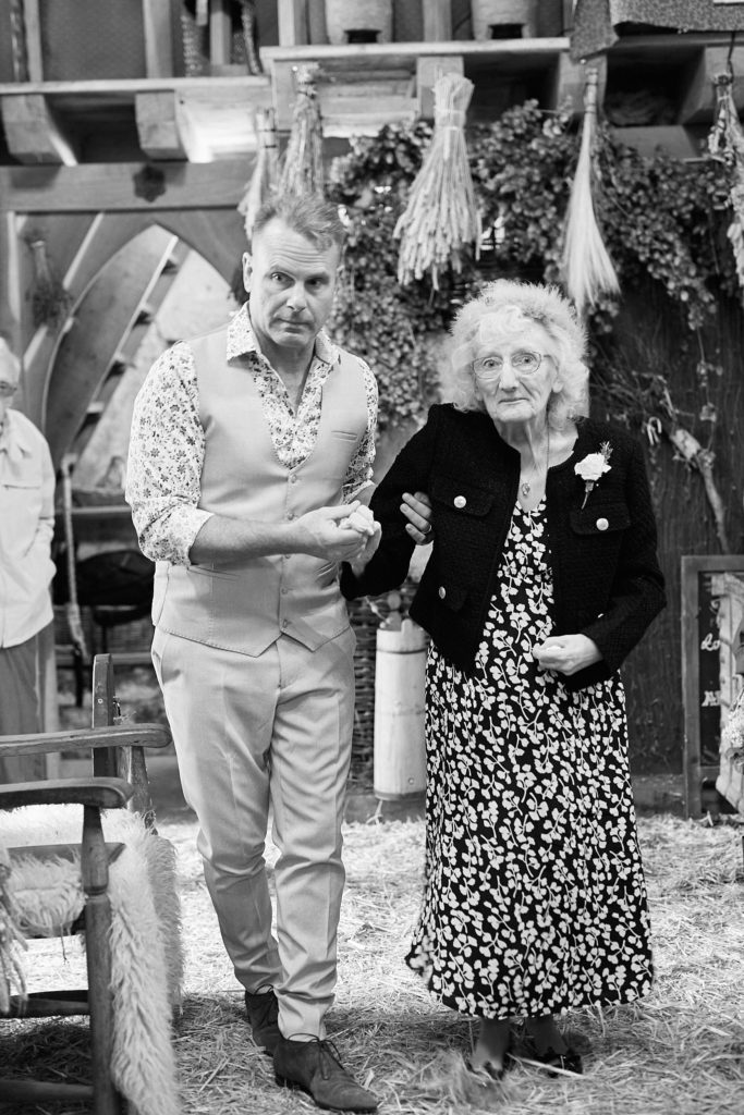 Black and white photo of the groom arm in arm with an elderly woman
