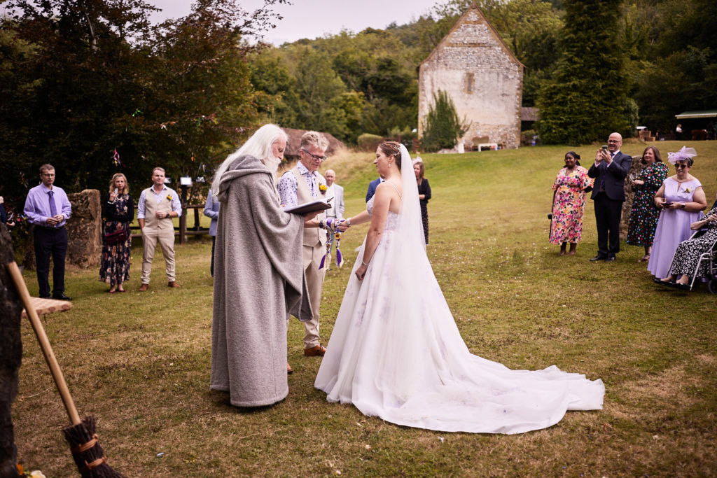Handfasting ceremony on the lawn with guests gathered round and the church beyond