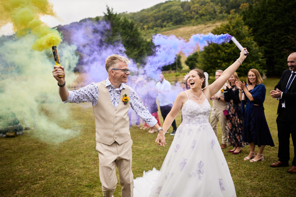 Bride and groom cheering as they wave smoke flares