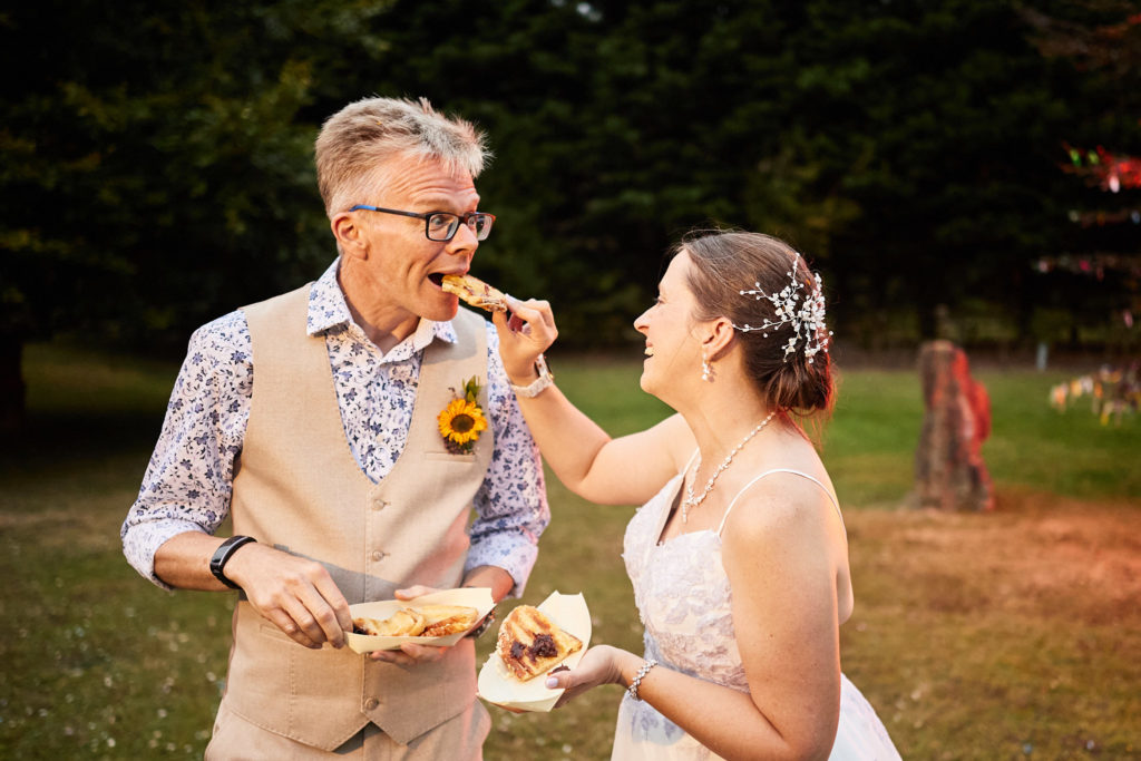 Bride feeding the groom a bite to eat outdoors