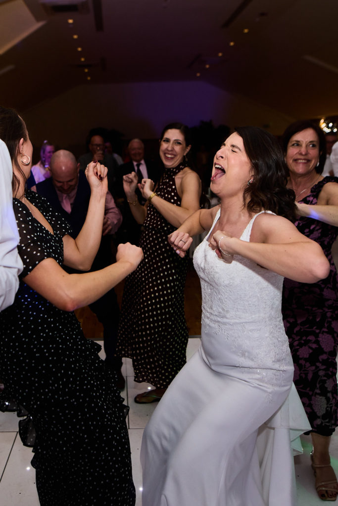Bride dancing with her eyes closed among guests on the dance floor
