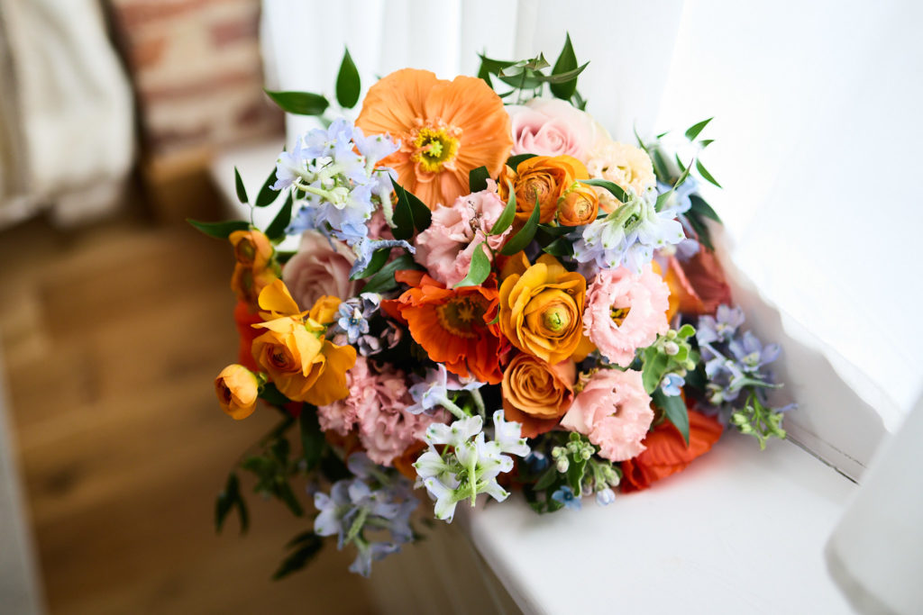 Bridal bouquet of orange, peach and blue flowers