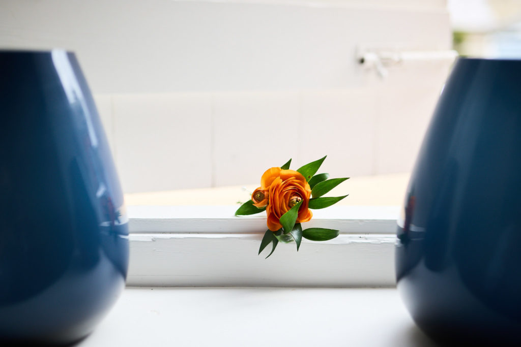 Orange buttonhole on a windowsill between two blue vases