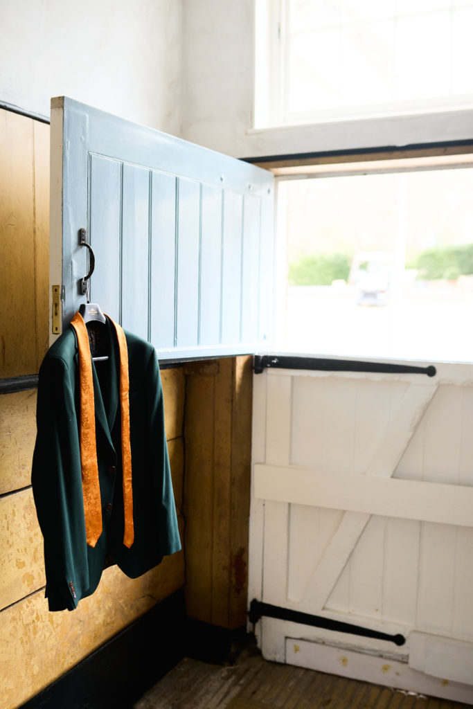 Green suit jacket and orange tie hanging on a pale blue stable door