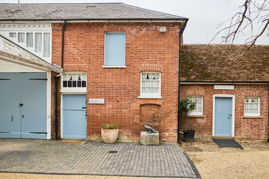 Red-brick coach house with pale blue doors at Hatfield Place