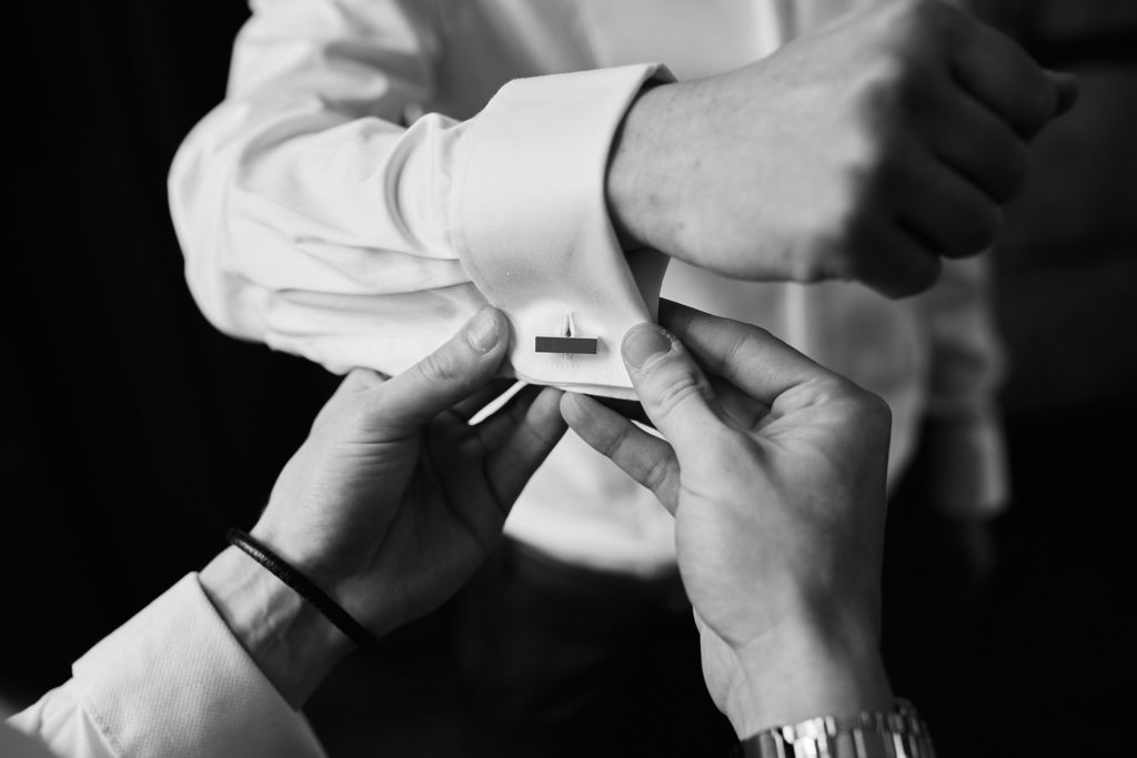 Black and white close-up of a cufflink being fastened