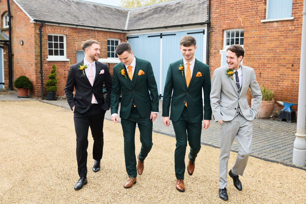 Groom and three groomsmen walking across the courtyard at Hatfield Place