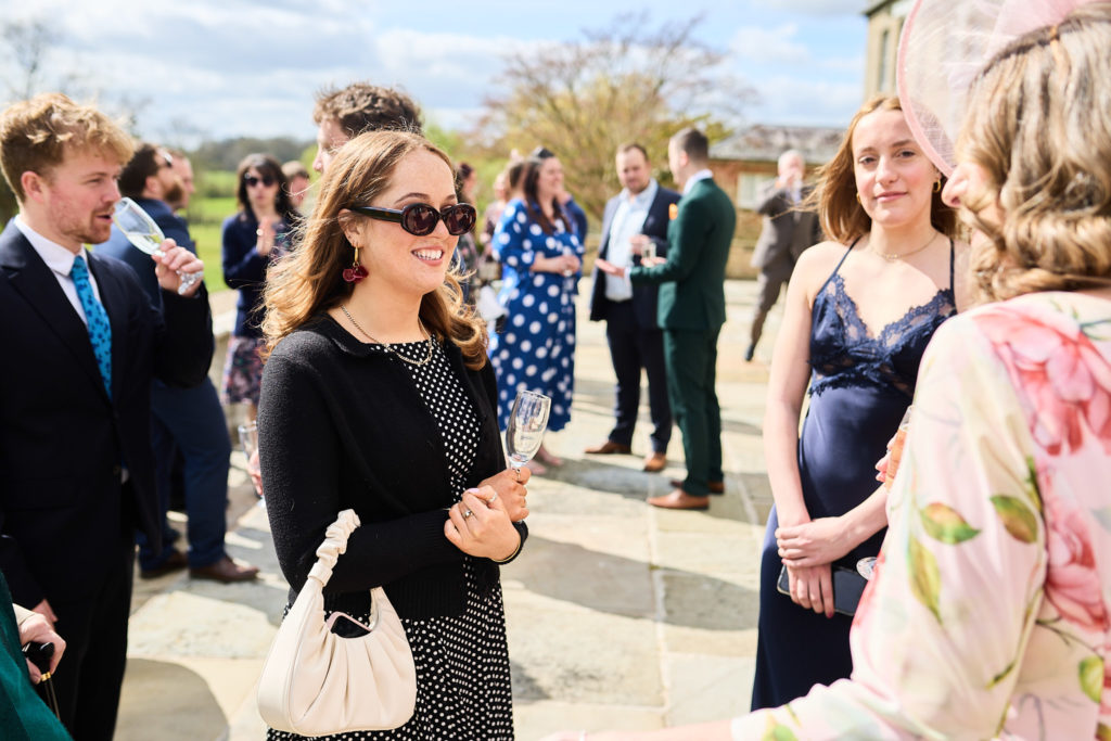 Wedding guests in sunglasses chatting outside in the sunshine