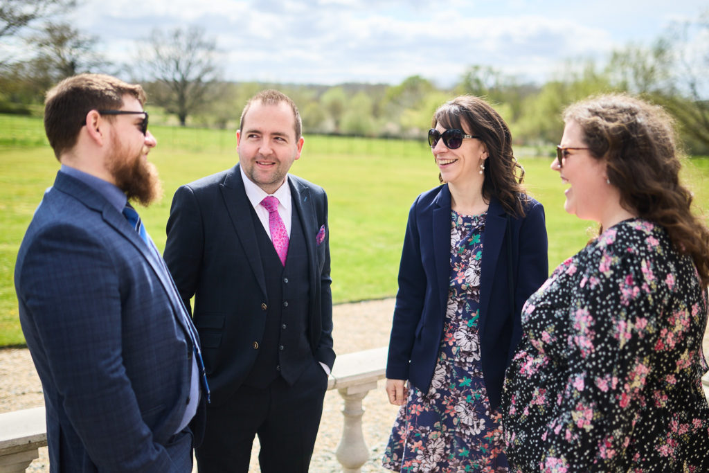 Four wedding guests chatting on the lawn