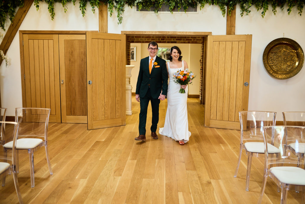 Bride and groom entering the oak-framed ceremony barn together at Hatfield Place
