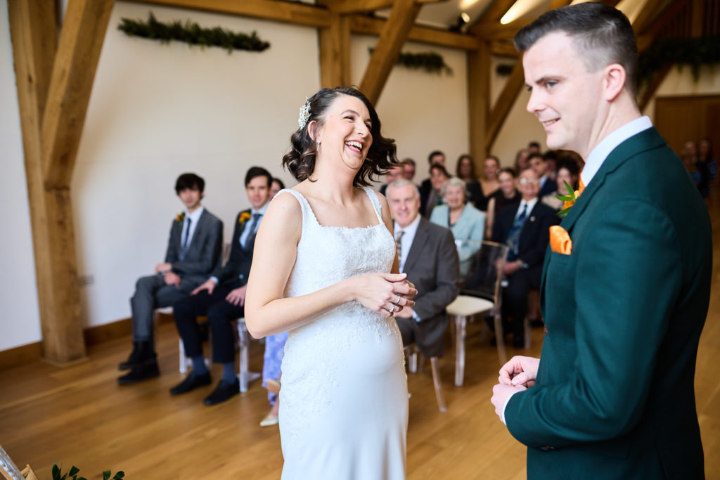 Bride laughing as she faces the groom during the wedding ceremony