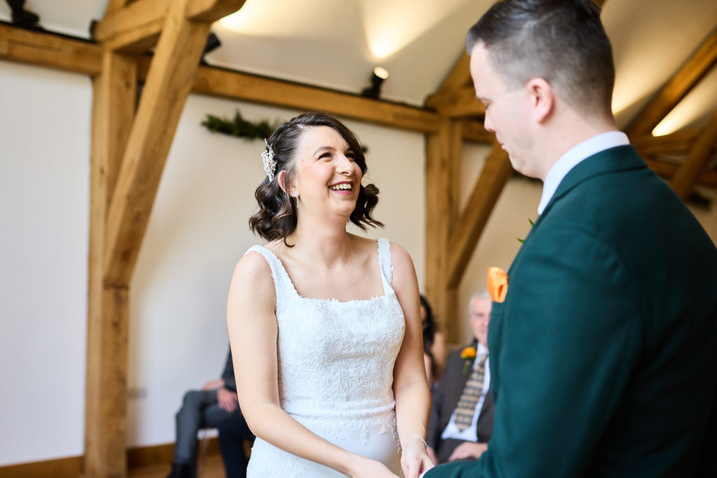Bride laughing as she looks up at the groom during the ceremony