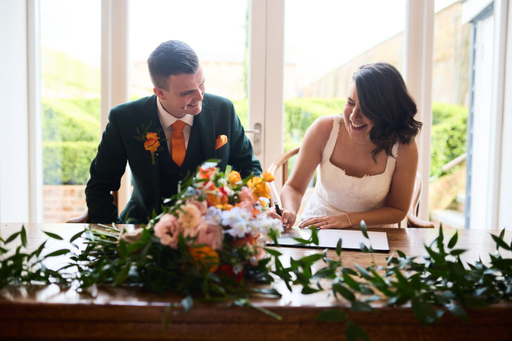 Bride and groom signing the register at a table decorated with flowers