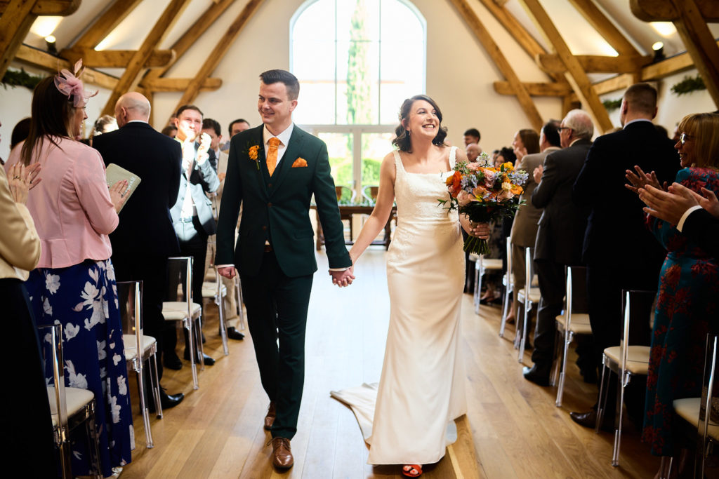 Bride and groom laughing as they walk down the aisle together