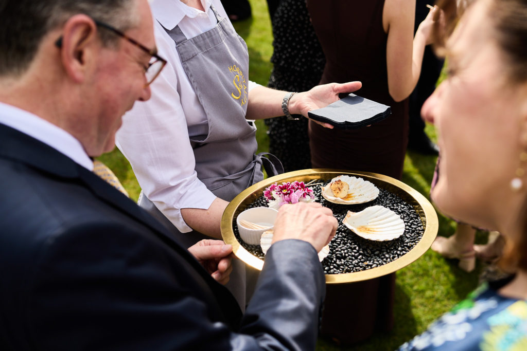 Wedding guest taking a canapé from a tray decorated with shells
