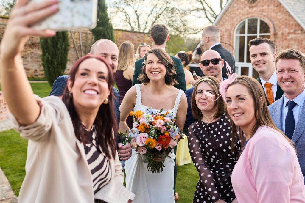 Wedding guest taking a selfie with the bride and a group of friends