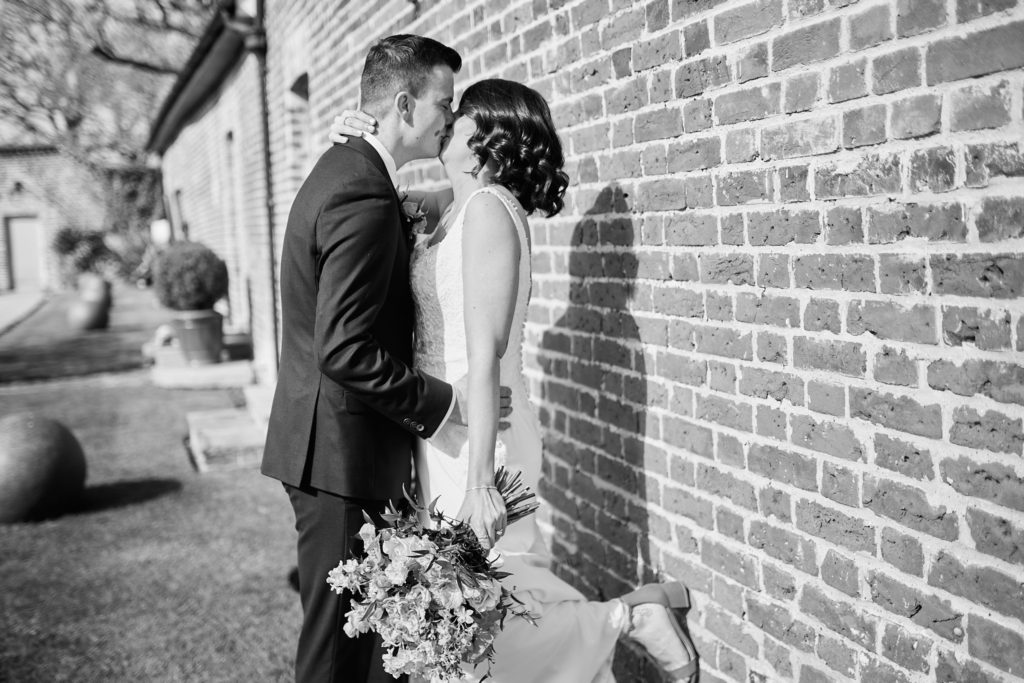 Black and white photo of the bride and groom embracing against a brick wall at Hatfield Place, Essex