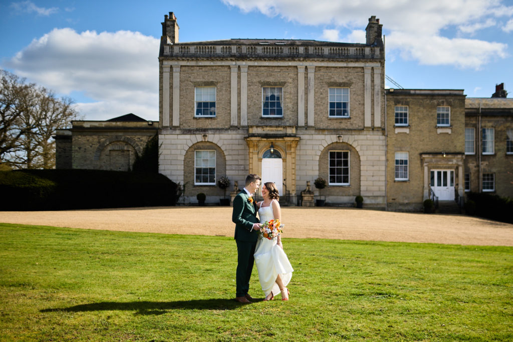 Bride and groom embracing on the lawn in front of Hatfield Place, Essex