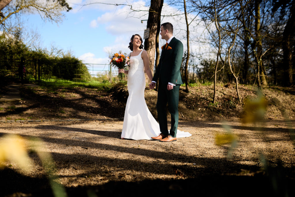 Bride and groom standing under the trees in the grounds of Hatfield Place